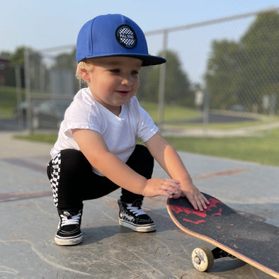 Blue toddler snapback hat, toddler with skateboard at skate park
