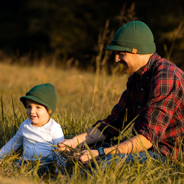 Shop online for beanies and snapback hats from LB Threads for babies, toddlers, kids and adults. Father and son model wearing the LB Threads Forest Green Visor Beanie, a warm, soft, forest green acrylic beanie with a flexible visor.