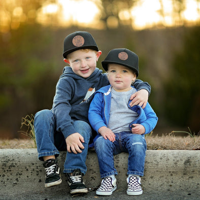 Shop online for snapback hats from LB Threads for baby, toddler, kid and adult. Models wearing the LB Threads Athens hat, a black classic snapback hat.