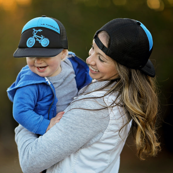 Shop online for snapback hats from LB Threads for baby, toddler, kid and adult. Mama and son models wearing the LB Threads BMX hat, a black and blue 7-panel snapback trucker hat.