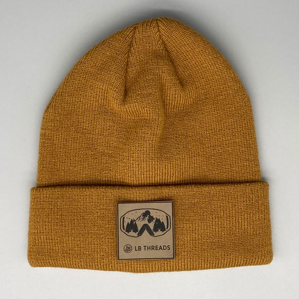 Shop online for beanies and snapback hats from LB Threads for babies, toddlers, kids and adults. Photo shows our Mountains Ahead Beanie, a warm, soft, black, tan or cream acrylic beanie with a colored leather ski goggles patch.