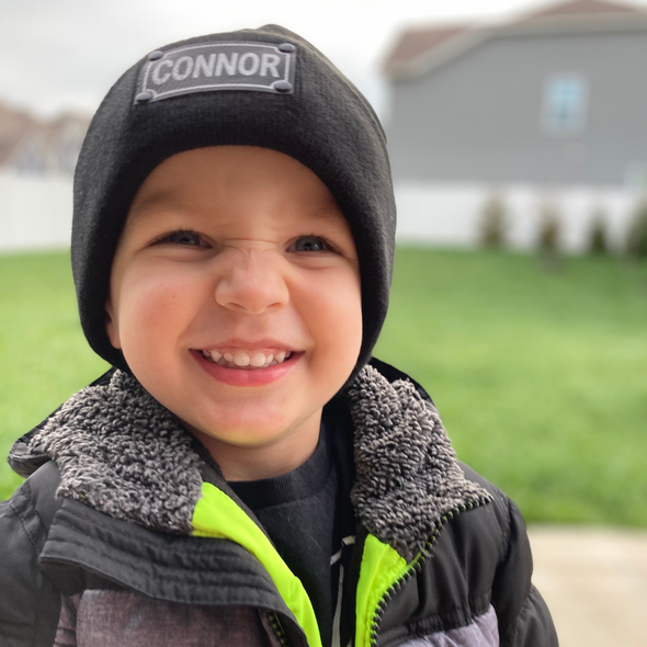 Shop online for beanies and snapback hats from LB Threads for babies, toddlers, kids and adults. Toddler model wearing our Black Custom Name Beanie, a warm, soft, black acrylic beanie with a leather engraved custom name patch attached with rivets.
