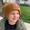 Shop online for beanies and snapback hats from LB Threads for babies, toddlers, kids and adults. Toddler model wearing our Tan Custom Name Beanie, a warm, soft, tan acrylic beanie with a leather engraved custom name patch attached with rivets.