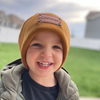 Shop online for beanies and snapback hats from LB Threads for babies, toddlers, kids and adults. Toddler model wearing our Tan Custom Name Beanie, a warm, soft, tan acrylic beanie with a leather engraved custom name patch attached with rivets.