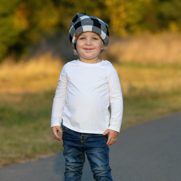 Shop online for beanies and snapback hats from LB Threads for babies, toddlers, kids and adults. Toddler model wearing the LB Threads White Buffalo Pom Beanie, a cozy, soft white buffalo plaid topped with a black faux-fur pom, lined with super soft black minky fleece for extra warmth.